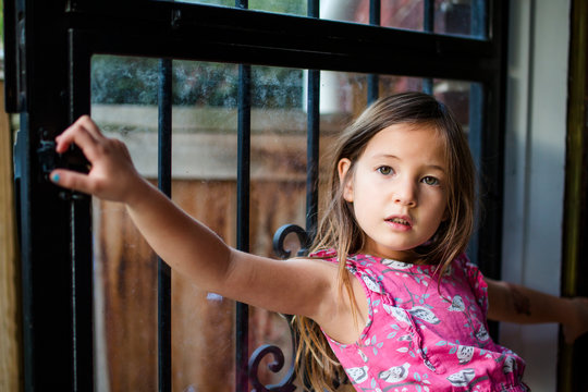 A Young Girl Stands Alone In An Open Doorway With A Direct Gaze