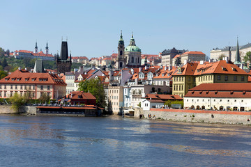 Obraz premium Spring green Prague baroque St. Nicholas' Cathedral with the Lesser Town above River Vltava in the sunny Day, Czech Republic