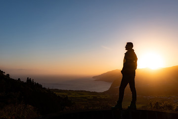 Man in beautiful inspiring sunrise with mountains and sea.