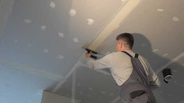 Amateur man apply joint compound between drywall panels