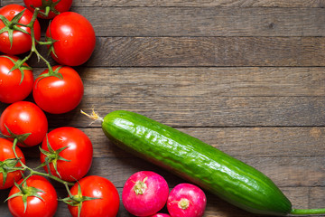 Ripe red tomatoes with radishes and cucumber on wooden desk