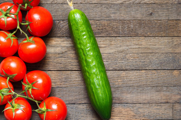 Ripe red tomatoes with cucumber on wooden desk