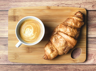 Perfect breakfast of croissant and coffee on wooden table. Rustic style.