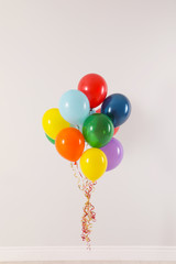 Bunch of bright balloons against light wall. Celebration time