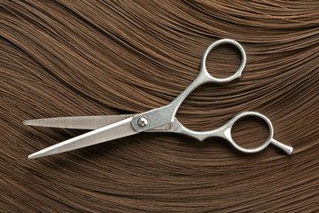 Scissors on brown hair, top view. Hairdresser service