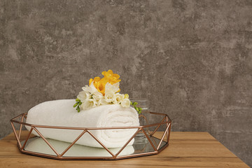 Rolled soft towel with beautiful flower in decorative tray on table. Space for text