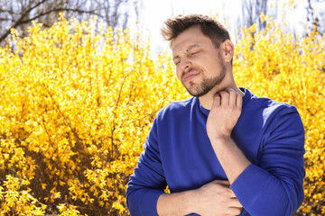 Man suffering from seasonal allergy outdoors, space for text