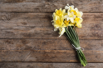 Bouquet of daffodils on wooden background, top view with space for text. Fresh spring flowers