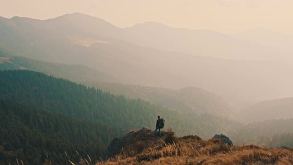 The male standing on the edge of a cliff in picturesque mountains