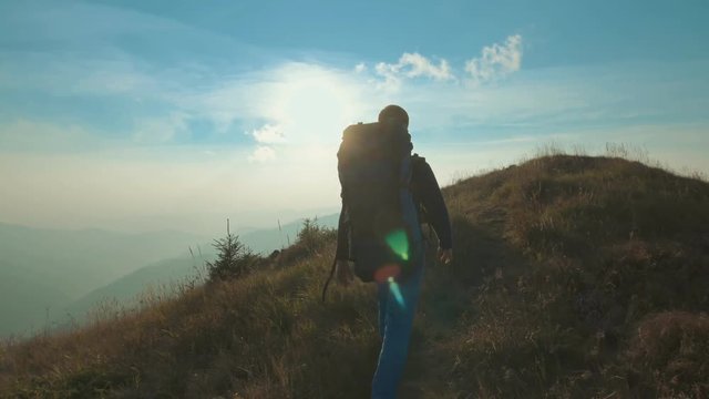 The man with a tourist backpack walking on the mountain