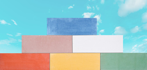 A pyramid of the multi-colored ceramic bricks made in a wall at the blue sky background