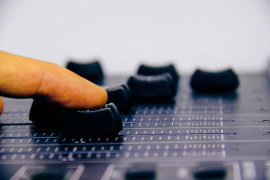 Audio mixer, mixing desk controls and fader, music mixing console with the hand of the technician moving the faders. Degraded effects for banners and backgrounds