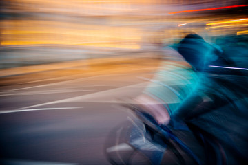 Front view of abstract defocused light-trails  of fast cyclist silhouette delivering food through...