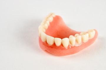 Artificial teeth on a white background with copy space, close-up