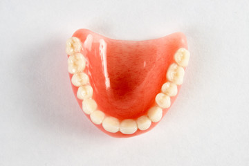 Artificial teeth on a white background with copy space, close-up