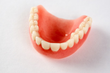Artificial teeth on a white background with copy space, close-up