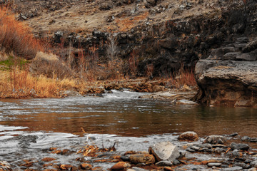 Beautiful view of a mountain river flowing between two high rocks with yellow plants in Turkey.