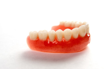 Artificial teeth on a white background with copy space, close-up