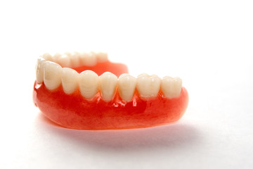 Artificial teeth on a white background with copy space, close-up