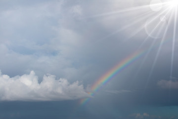 Rainbow in the blue sky with lighting flare