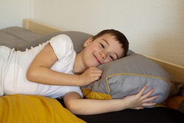 The boy with a smile on his face lies in bed, close-up