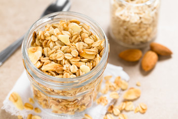 Homemade baked crunchy oatmeal, sliced almond, honey and coconut oil breakfast granola in glass...