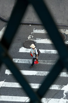Woman walking along a crosswalk while carrying shopping bags, in New York City's Chinatown district in Downtown Manhattan, NYC, NY