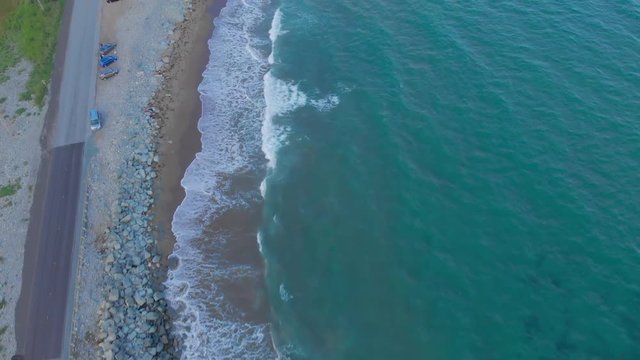 Cinematic drone / aerial footage moving forwards showing a road by the ocean and waves hitting the beach at Cole Harbour coast in Lawrencetown, Nova Scotia, Canada during summer season.