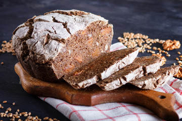 Yeast free homemade sliced bread with whole rye and wheat grains on black wooden background.