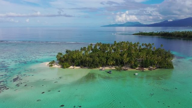 Aerial drone video from French Polynesia of Motu Mahaea, Tahaa, Tahiti. Aerial view of Paradise island with palm trees and turquoise blue water in coral reef lagoon Tahiti, South Pacific Ocean.