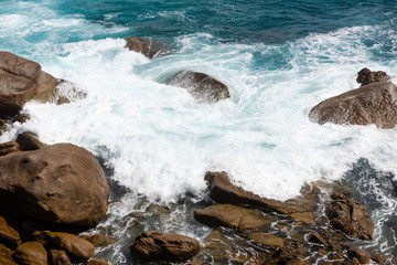 Big ocean splash near coast with rocks