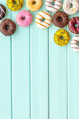 Glazed decorated donuts for sweet break on mint green wooden background flat lay copy space