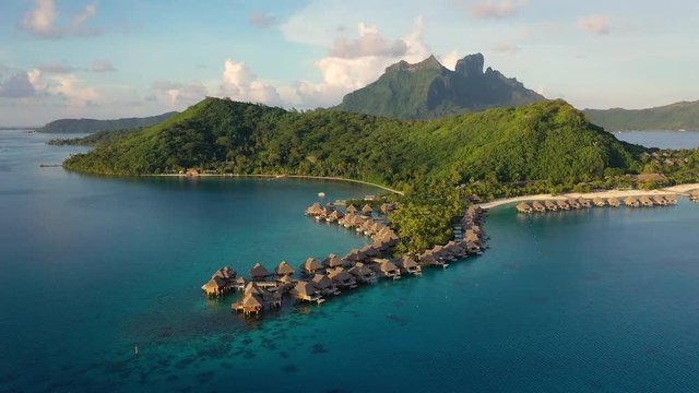 Aerial drone video of Tropical vacation paradise island with overwater bungalows in coral reef lagoon ocean beach. Mount Otemanu, Bora Bora, French Polynesia, Tahiti, South Pacific Ocean.