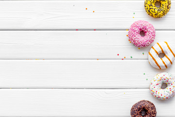 Traditional american donuts of different flavors on white wooden background flat lay mockup
