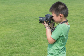 A boy taking photo on green grass