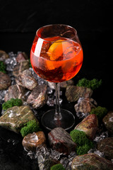 Aperol syringe soft alcoholic drink on a black background with stones and ice. Cocktail card for a bar or restaurant.