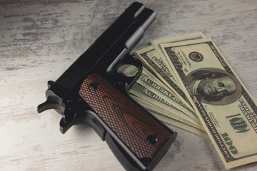 a gun with money on a wooden table