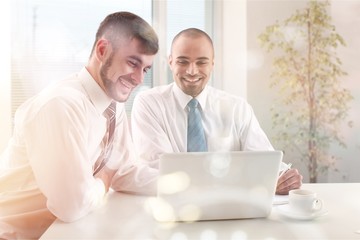 Young men using laptop in office