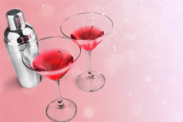 Glasses of red martini with cherries and silver shaker on white background