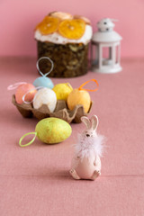 Easter decor with colorful eggs, Easter traditional cake and a pink cute bunny on a pink background.