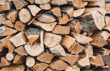 Many logs and firewood lie on top of each other as background and texture, ready to heat. Preparation for the heating season.