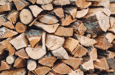 Many logs and firewood lie on top of each other as background and texture, ready to heat....
