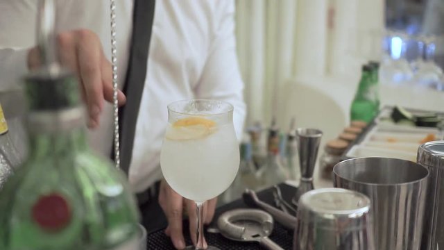 barman prepares a gin. orbiting shot around the drink