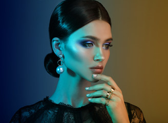 High Fashion model woman in colorful bright lights posing in studio.