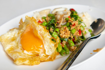 Close up of rice topped with stir-fried pork squid and basil.