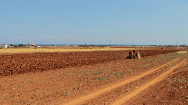 A tractor opening the ground, agriculture, farming. Red soil.