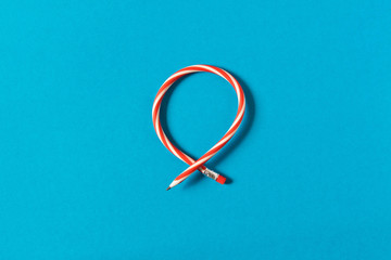 Flexible pencil . Isolated on blue background. Bending pencil.