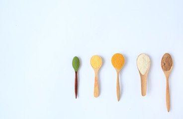 Various colorful powder in different wooden spoons with copy space isolated on white background.
