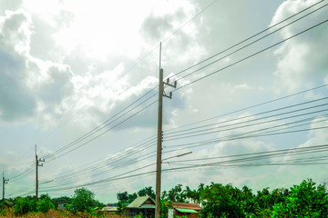 Electricity pole against blue sky clouds, Transmission line of electricity to rural with green...