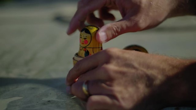 Hands break apart a Russian doll.